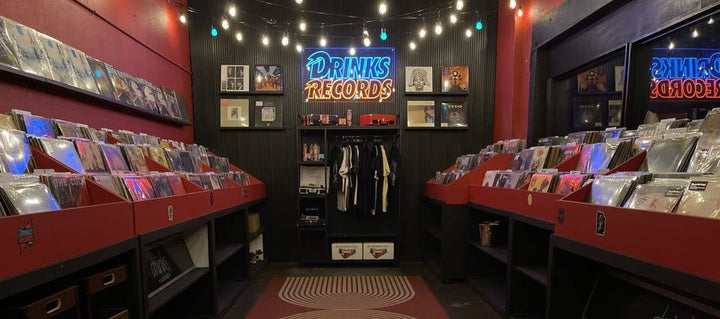 Red vinyl bins and the illuminated Drinks Records sign inside the East Austin shop.