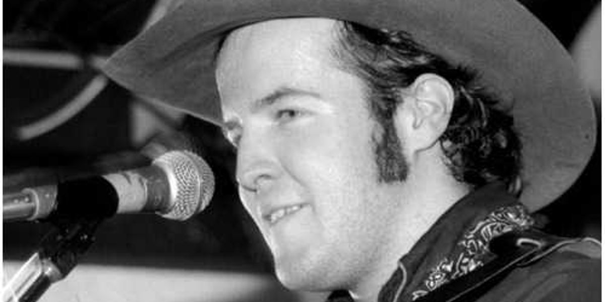 Handsome Ned wearing a cowboy hat and singing into a microphone